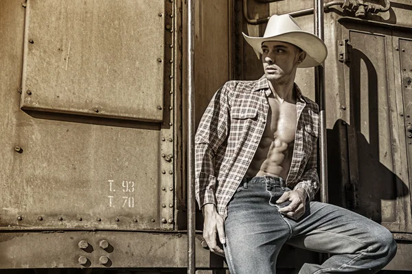 Sexy topless cowboy posing against old train