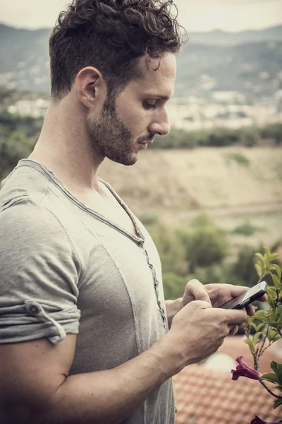 Handsome trendy man using cell phone to type text