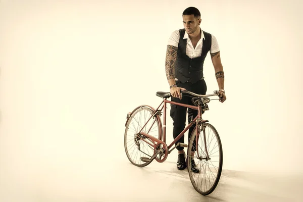 Tattoed elegant man cycling on bicycle