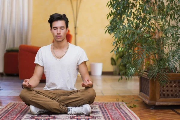 Young man meditating on his living room floor