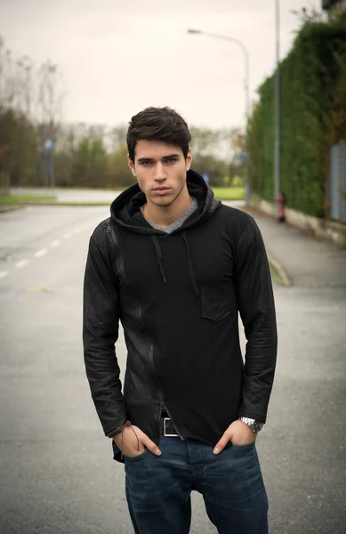 Handsome young man in black hoodie sweater outdoor in street