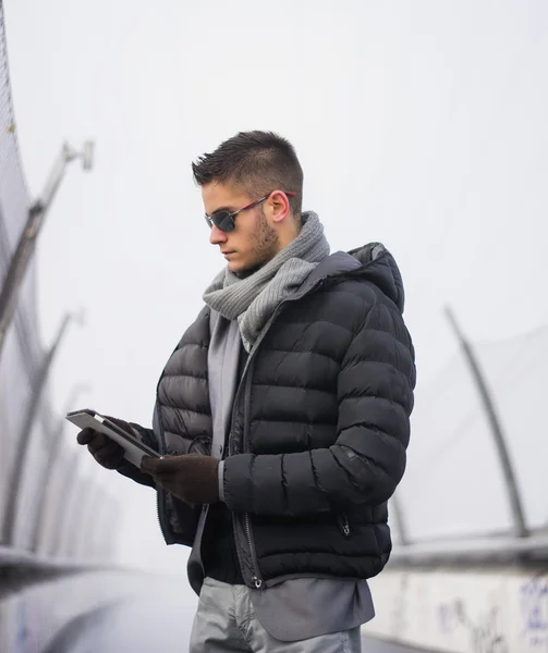 Handsome trendy man in winter jacket with tablet PC