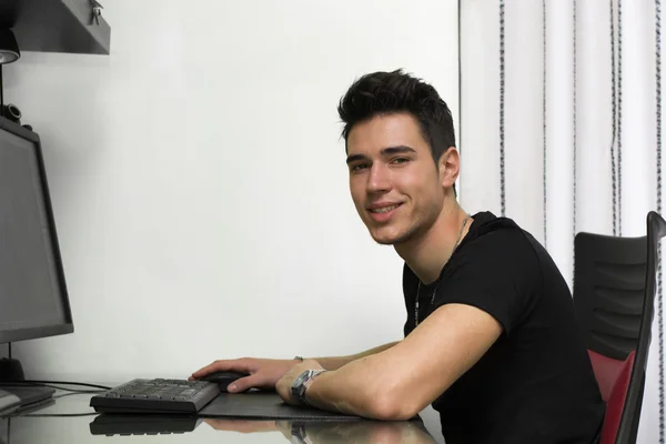 Handsome young man working or studyiing at computer