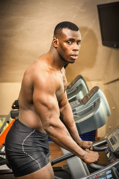 Black male bodybuilder exercising on treadmill