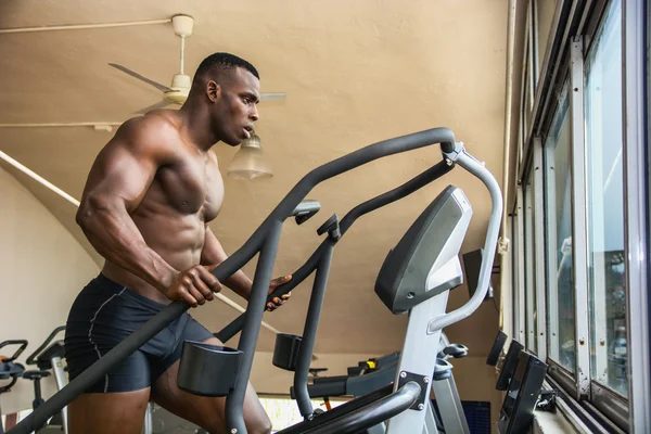 Black male bodybuilder exercising on step machine