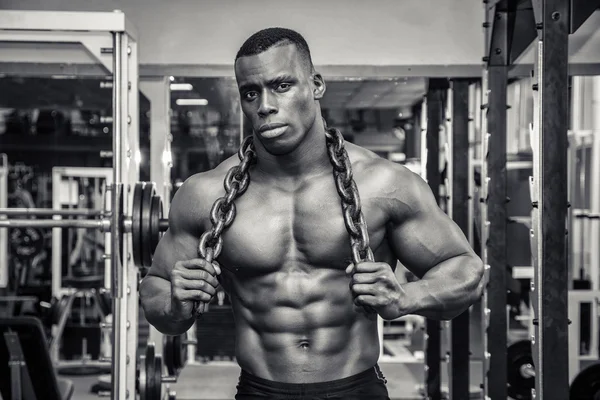 Attractive hunky black male bodybuilder posing with iron chains