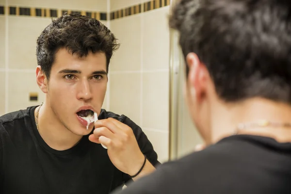 Headshot of attractive young man brushing teeth