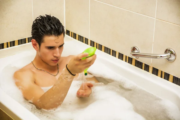 Handsome young man in bathtub at home having bath