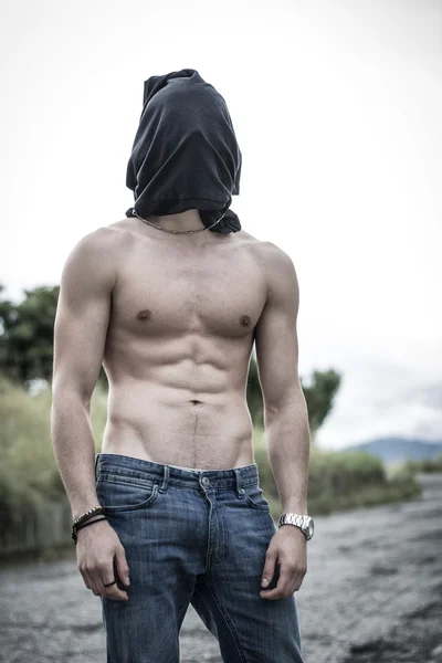 Naked mans body, head covered with t-shirt