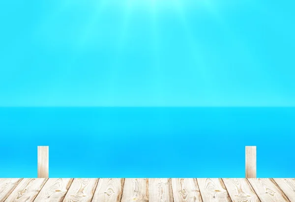 Bright wooden pier on the blue sea blur background. Cloudless sky merges with the sea surface during the calm.