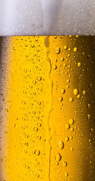 Overflowing beer in a glass with dew drops