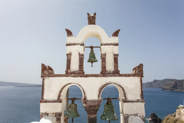 White bell tower with green bells on top of a chapel in Oia (Ia) Santorini (Thera) Greece