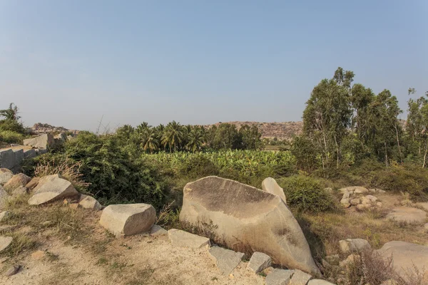 Landscape of rocks and green fields in the ancient site of Hampi, Karnataka - India - Asia