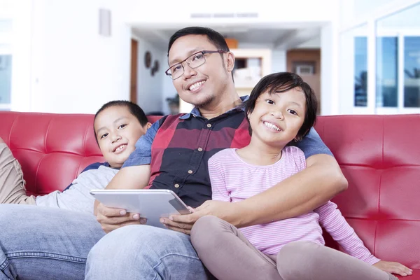 Happy children and dad with tablet on sofa