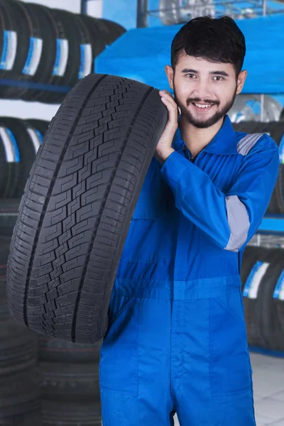 Mechanic carrying tire in the store