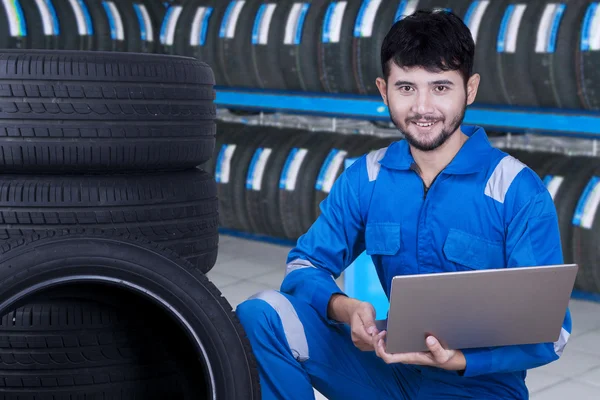 Mechanic using laptop to check tires