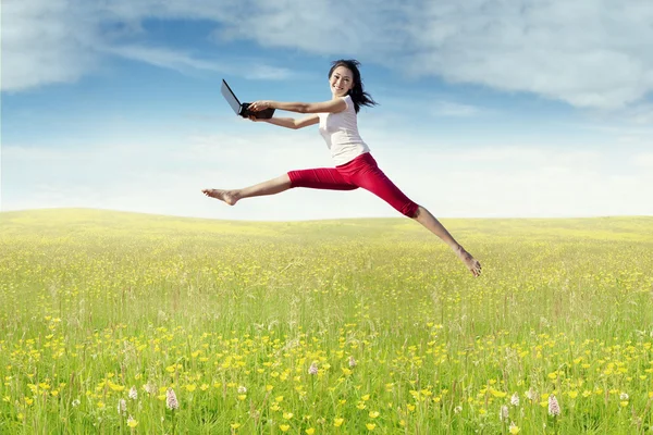 Woman with laptop leaps in the nature