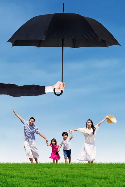 Family running under umbrella outdoors
