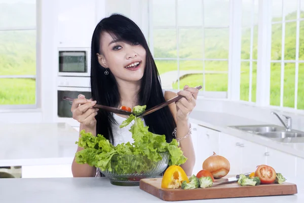 Asian woman mixing salad on a bowl