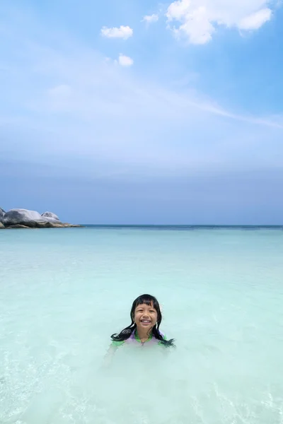 Cheerful little girl smiling at the camera on beach