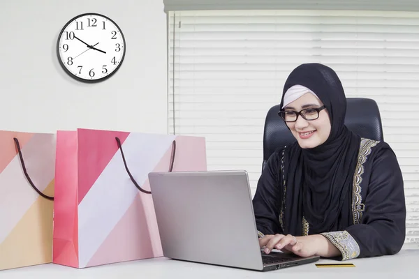 Pretty Arabic woman shopping online in office