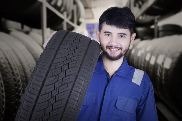 Mechanic carrying tire in the store