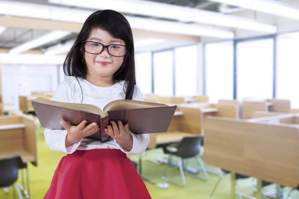 Little girl holds book in reading room