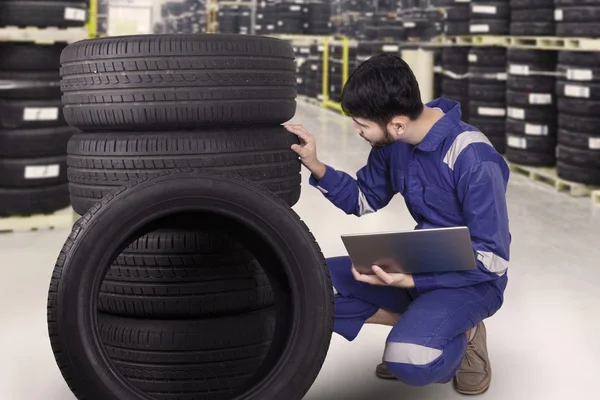 Young mechanic checks a pile of tires