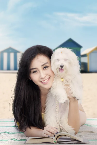 Attractive girl with dog and book at shore