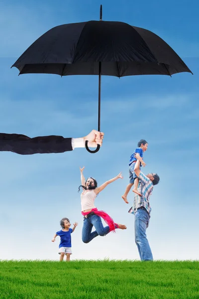 Family jumping under umbrella on the meadow