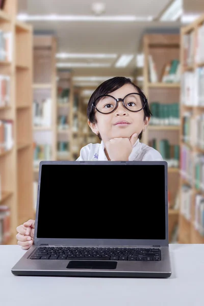 Pensive girl with laptop in library