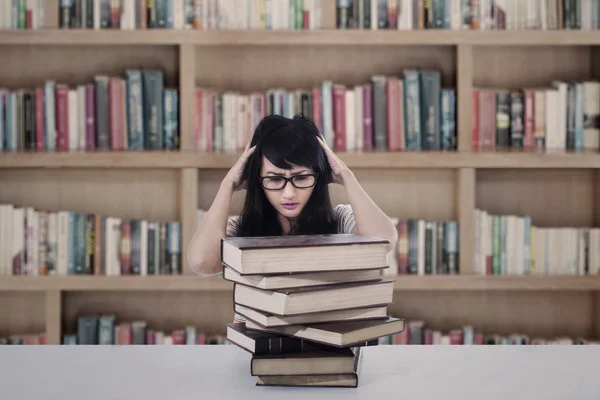 Attractive female student stress looking at books in library
