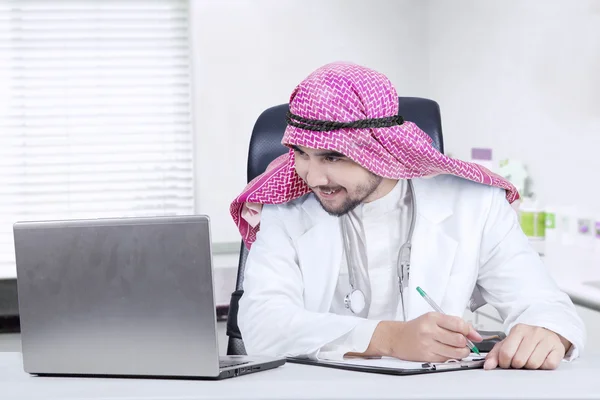 Male physician works with laptop in clinic