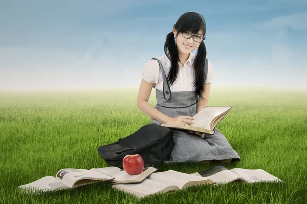 Chinese student reads books on meadow