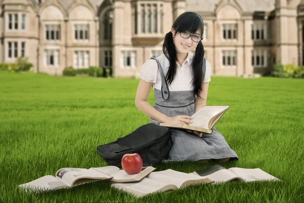 Pretty Chinese student reads books at park