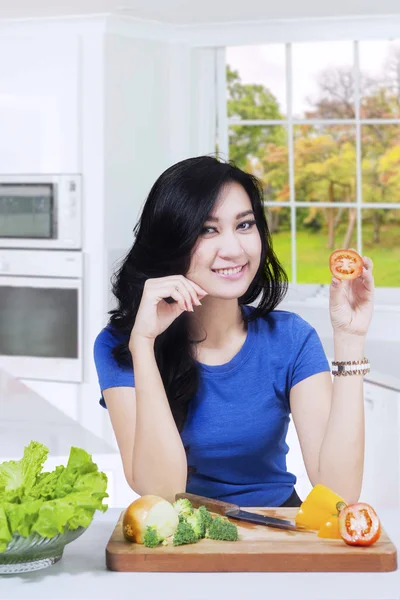 Vegetarian woman holds tomato in kitchen