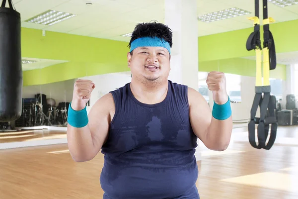 Cheerful fat man in fitness center