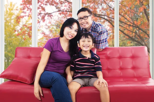 Family sitting on sofa and smiling at camera