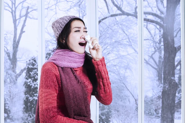 Woman in winter clothes sneezing