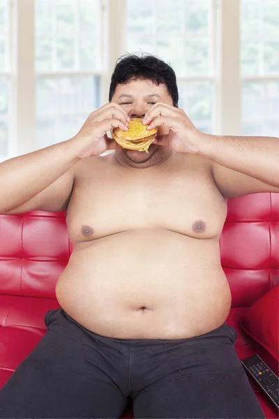 Obesity person eating burger on sofa