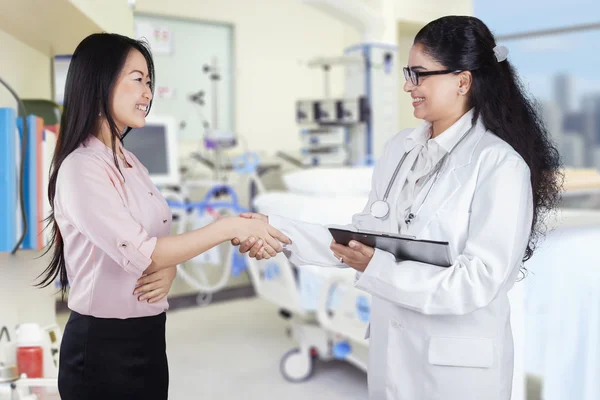 Friendly doctor shaking hands with patient in the clinic