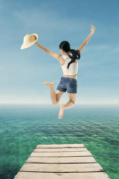 Young woman jumping at pier