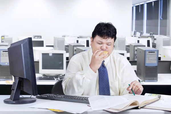 Entrepreneur working while biting burger