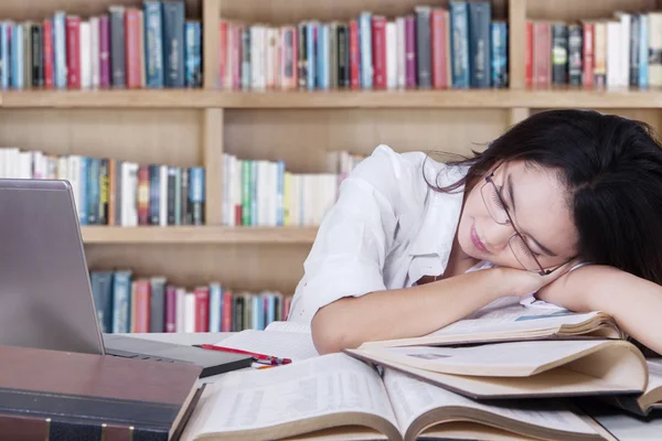 Female student sleeping over books