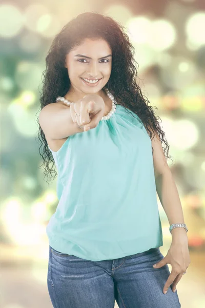 Woman pointing at camera with blur background