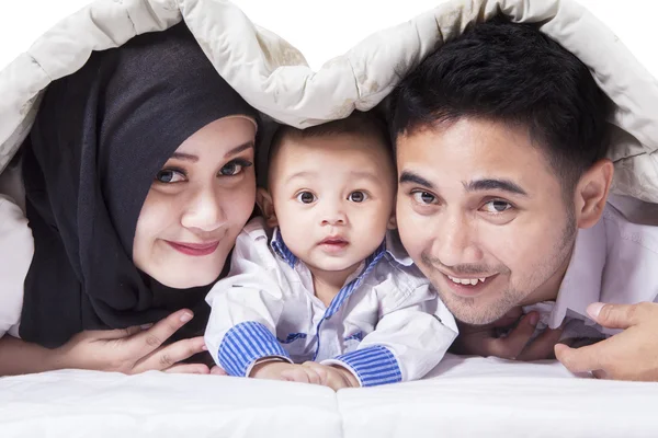 Family smiling on the camera under the blanket