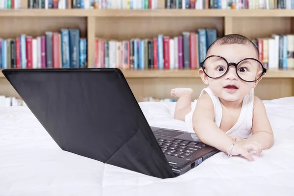Male baby with laptop and a bookshelf background