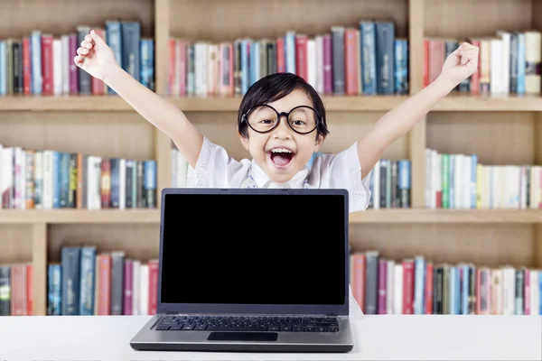 Successful child raise hands with laptop in library
