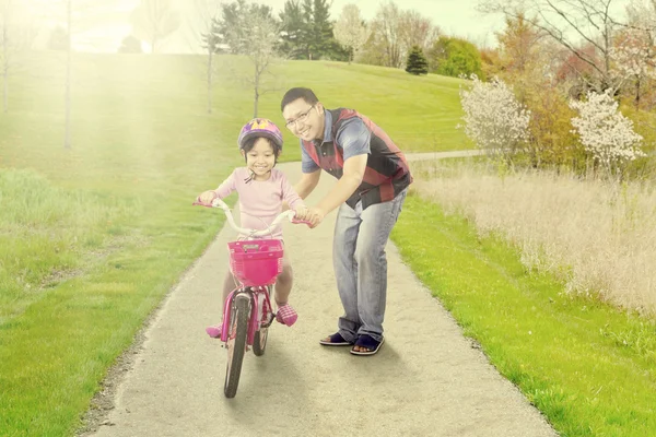 Dad trains his daughter to ride a bike