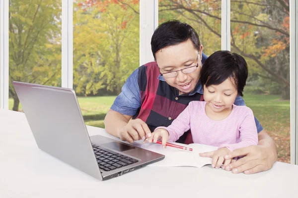 Father teach his child doing homework with book